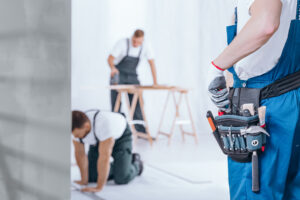Close-up of handyman wearing gloves and tool belt on blue trousers during home renovation