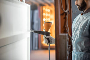 Painter in protective wear paints metal products with powder paint. Powder coating process at the manufacturing. High quality photo