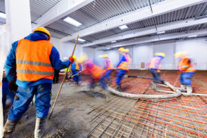 Workers do concrete screed on floor with heating in a new warehouse and office building. Interior finishing industry.